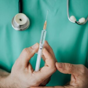 Doctor holding a syringe, ready for injection, with stethoscope.